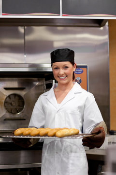 Smiling young baker with baguettes