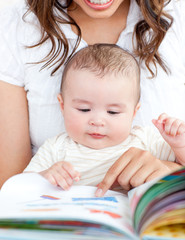Bright mother showing images in a book to her cute little son