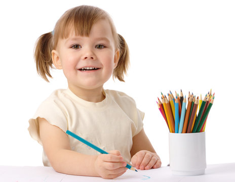 Cute child draws with color pencils