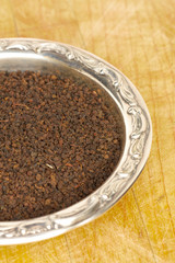 Loose black tea leaves in a sterling silver dish