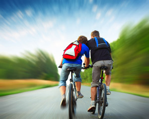 Two riders with backpacks on bikes riding on a rural asphalt roar