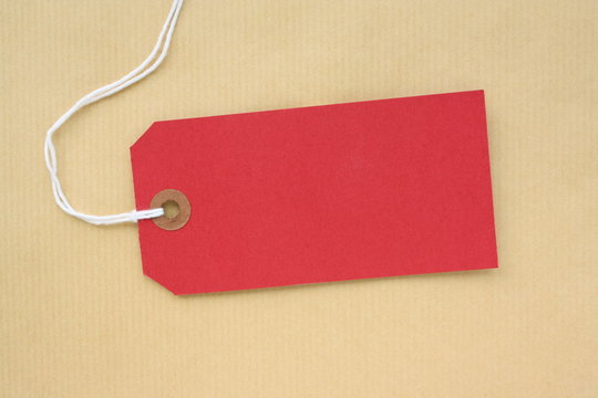 Red paper luggage tag on brown wrapping paper background