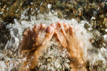 woman feet pounded by wavs on the pebble beach