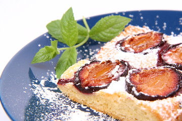 Piece of Plum Pie with powder sugar decorated with a mint twig