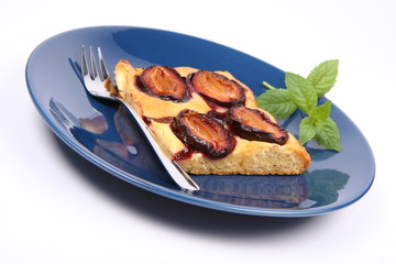 Piece of Plum Pie on a blue plate decorated with a mint twig