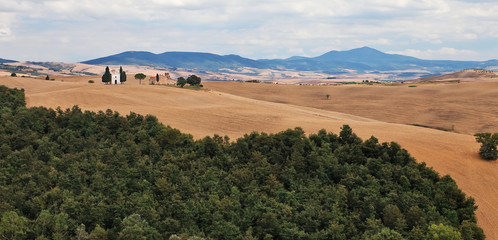 Small chapel on a hill in Tuscan farmland.