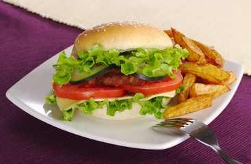 Hamburger with French fries and fork (Selective focus)