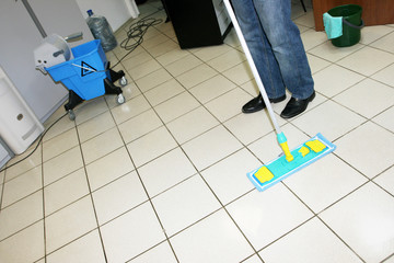 A man washing floor in the office with a swab
