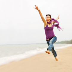 Beautiful young woman taking a great leap on the beach