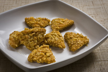 Triángulos de pollo rebozados con cereales.