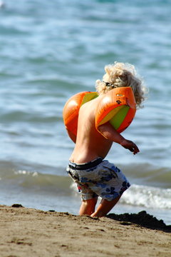 Baby play on the seashore with water wings