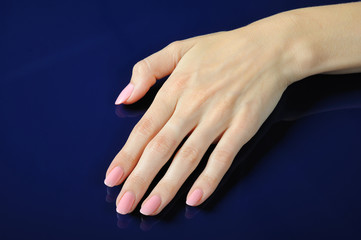 Beautiful hands with perfect nail pink manicure. isolated on blu