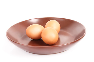 Three brown hen's eggs in the flat plate isolated on white