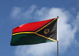 Vanuatu flag flying in the wind with slightly cloudy background