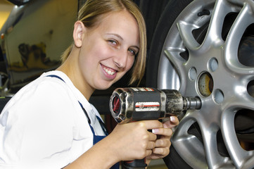 Frau macht Reifenwechsel in der Autowerkstatt