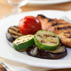 Grilled vegetables and chicken breast on white plate