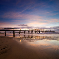pier at dawn with reflections and smooth clouds