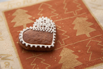 Lebkuchen als Herz auf Untergrund mit weihnachtlichem Motiv