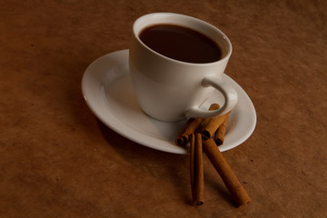 cup of coffee with cinnamon on a old paper background.