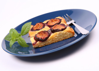 Piece of Plum Pie on a blue plate decorated with a mint twig