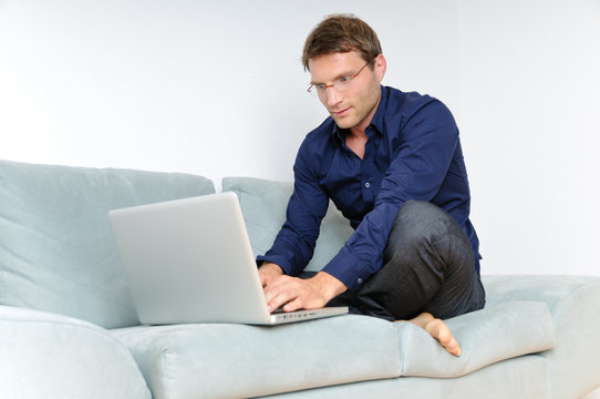 Young man relaxing with laptop on a couch