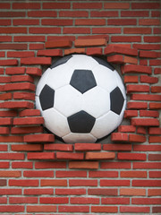 A soccer ball wedged into a brick wall