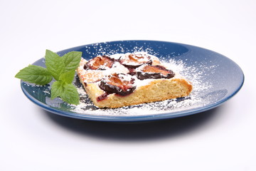 Piece of Plum Pie covered with powder sugar with a mint twig