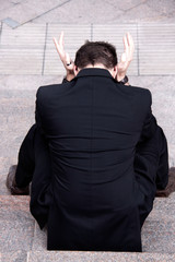 Anonymous businessman in black suit in crisis posture 