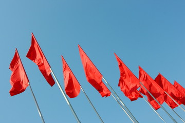 Red flags sway in the wind against a blue sky
