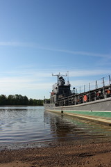 Transport military barge at the river bank against a blue sky
