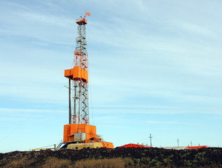 Orange oil derrick against blue sky
