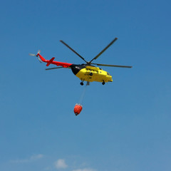 Fototapeta na wymiar Fire rescue helicopter with water bucket - Square crop