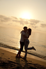 Fototapeta na wymiar Couple kissing in sunrise at the beach.