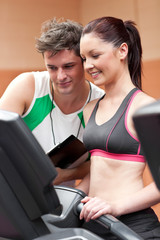 Joyful female athlete standing on a running machine with her per