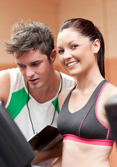 Cheerful female athlete standing on a running machine with her p