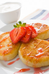 Cheese pancakes with sour cream, syrup and strawberry