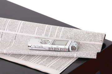 Diktafon and the newspaper on black table isolated on white back