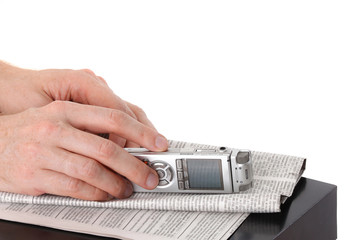 Dictaphone in male hand and newspaper