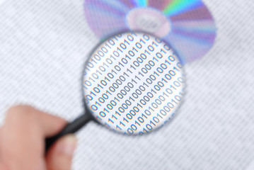 magnifying glass with DVD on binary code