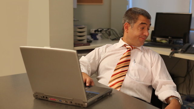 Tired businessman using laptop in office