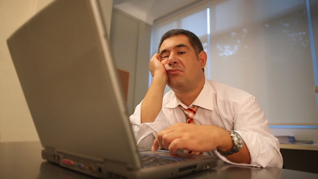 Tired businessman using laptop in office