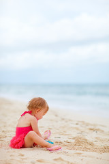 Toddler girl playing with toys at beach