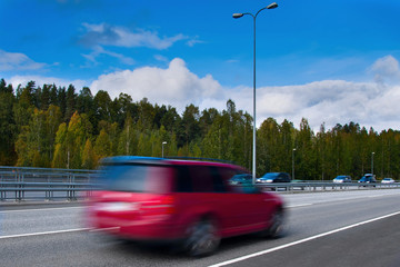Obraz na płótnie Canvas Fast driving red car on high way - motion blur