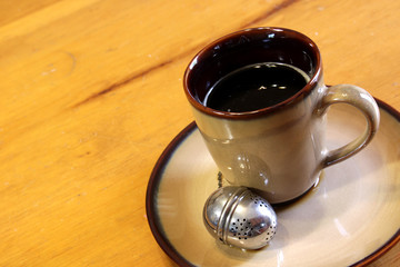 Obraz premium A tea strainer sitting next to a mug of hot freshly brewed tea..