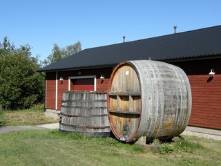 Big barrels on a lawn near a wooden cottage or cellar