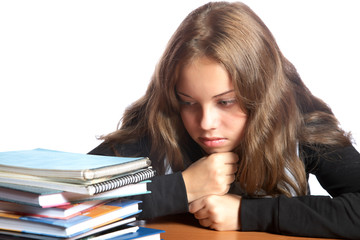 The girl-teenager looks at  pile of books