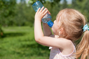 A little girl is drinking clean water from a bottle