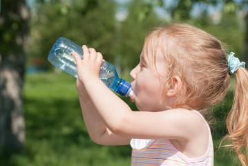 A little girl is drinking clean water from a bottle