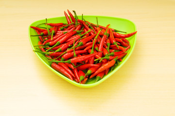 Hot peppers in the plate on wooden table