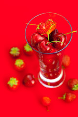 glass of cherry and strawberry on a red background